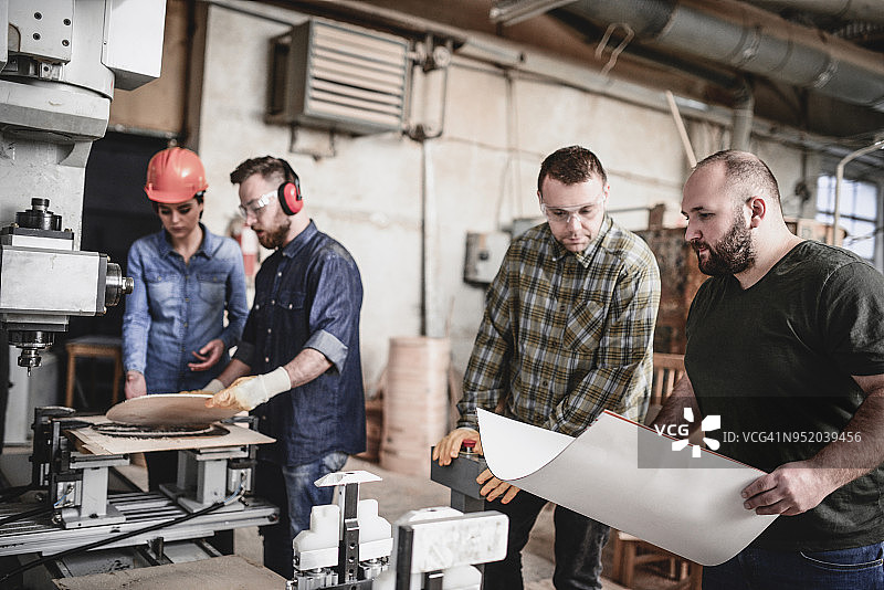 木匠在车间制作椅子并接受高级主管的修订图片素材