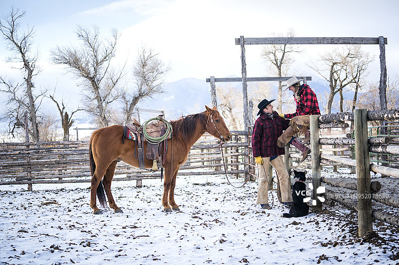 穿着格子夹克在牧场马厩里交谈的情侣图片素材