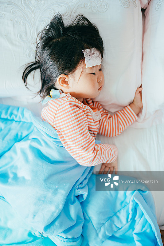 生病的亚洲小女孩在床上睡觉图片素材