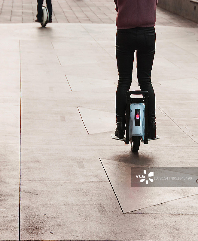 女子骑电动独轮车在人行道上行驶的背影图片素材