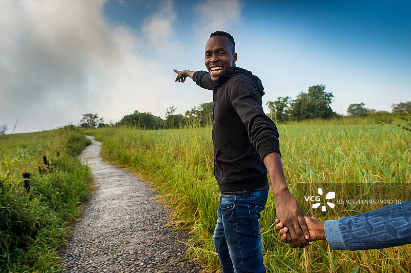 男友牵着女友的手在小路上指点并微笑图片素材