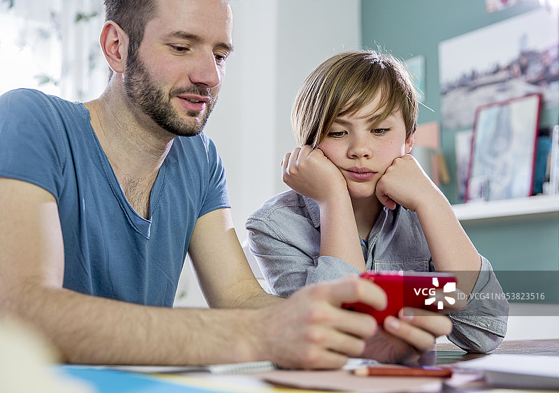 三十多岁的男导师为10岁金发小学生辅导家庭作业图片素材