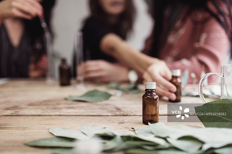 女同事在工作室的桌子上调制香水（中部视角）图片素材