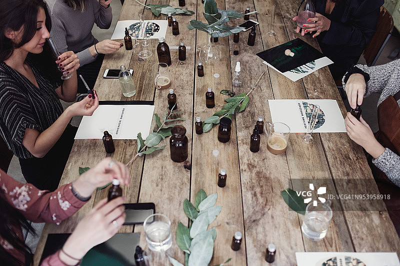 工作坊中在桌旁准备香水的多民族女同事高角度视图图片素材