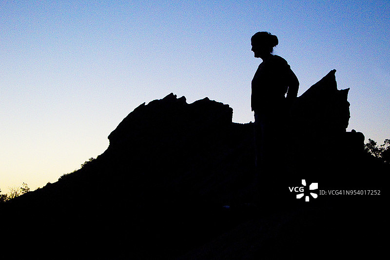 夕阳下瓦斯奎巨岩的女人剪影图片素材