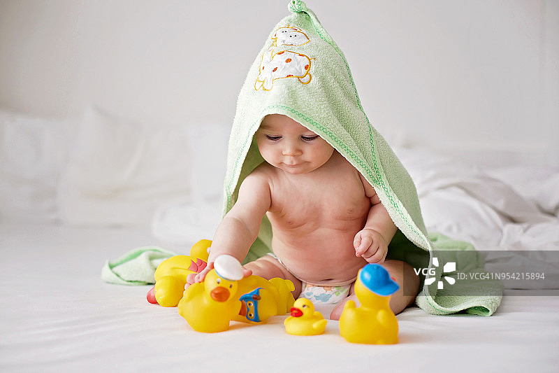 浴后在床上玩耍小鸭子的可爱男宝宝图片素材