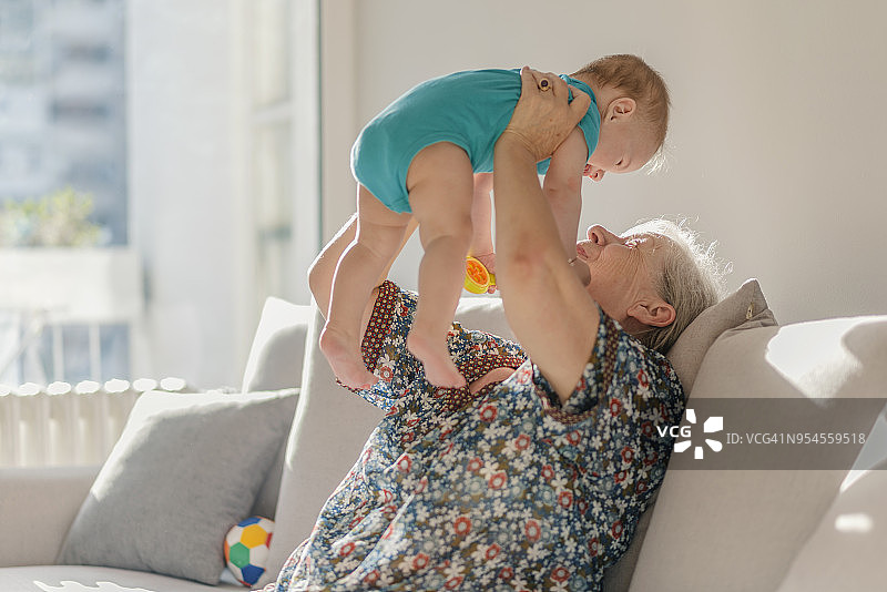 祖母在家坐在床上照顾小孙子图片素材