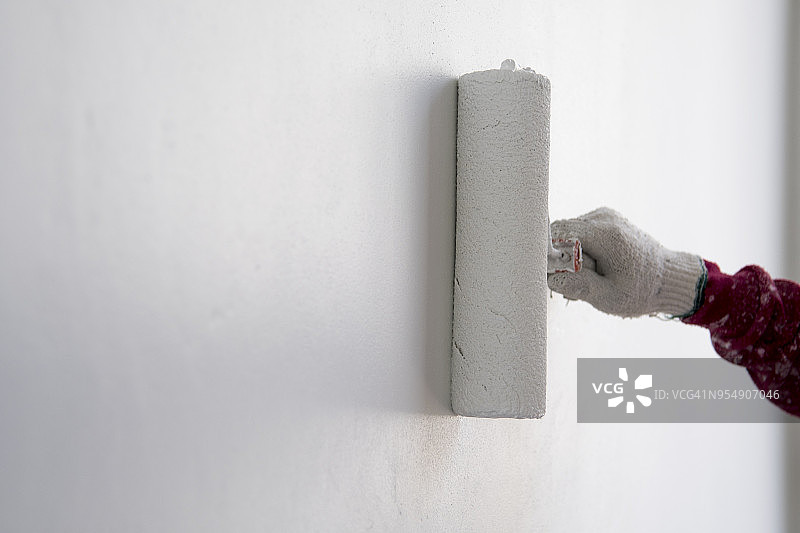 建筑工人在新水泥墙上使用滚筒刷油漆图片素材