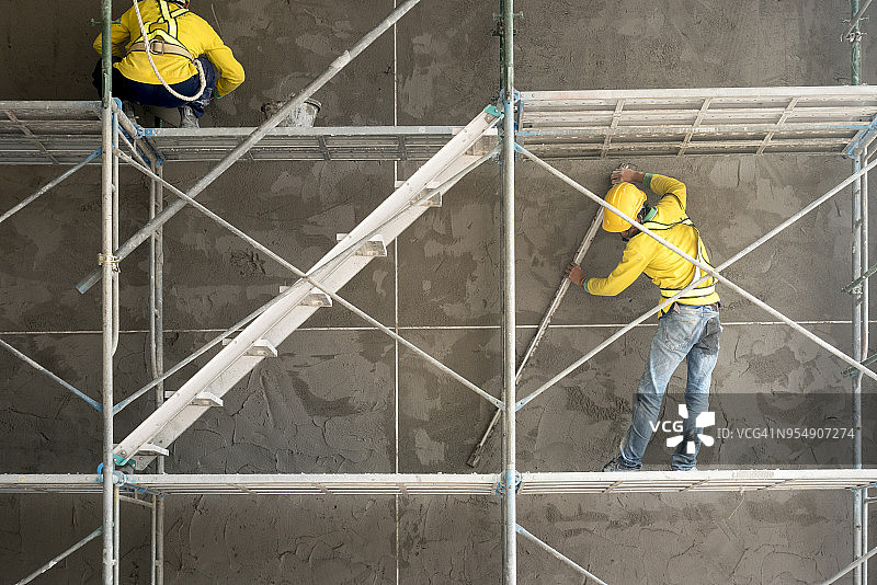 在混凝土砌块墙上抹水泥的建筑工人图片素材
