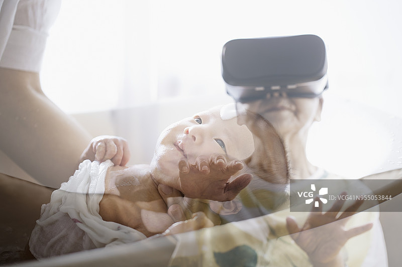 年长的女人戴着VR头显，在虚拟现实世界中与婴儿交流图片素材