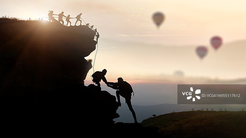 男女登山者攀登悬崖剪影图片素材
