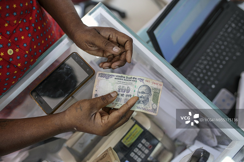 顾客手持印度100卢比纸币图片素材