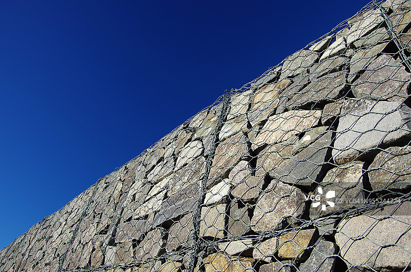 蓝色天空下的金属网石 retaining wall图片素材