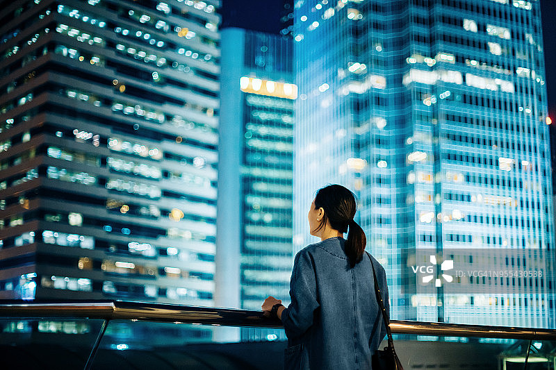 女子在夜晚俯瞰中国香港标志性城市景观的背影图片素材