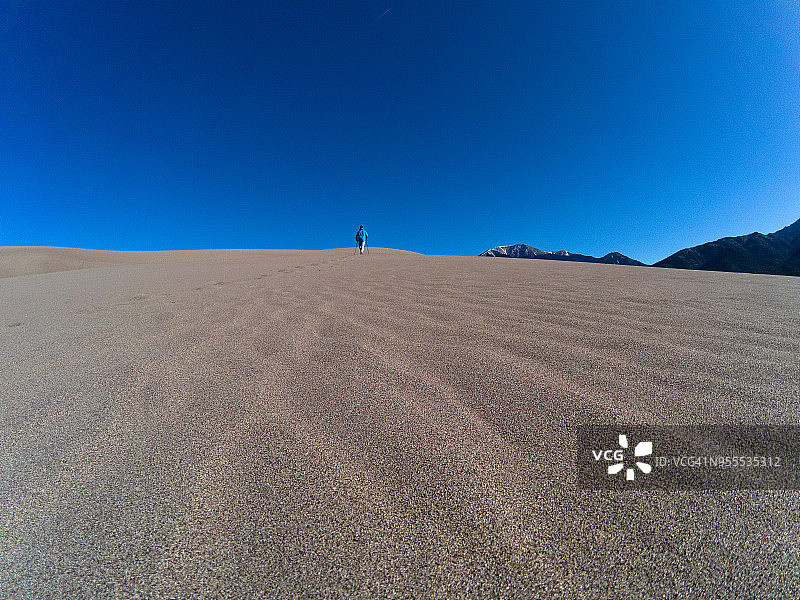 男子在日落时分徒步沙丘图片素材