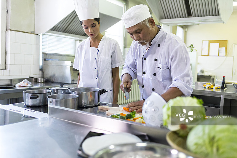 年长的厨师在亚洲餐厅切胡萝卜图片素材
