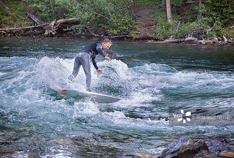 穿着灰色潜水服的男人在河中冲浪图片素材