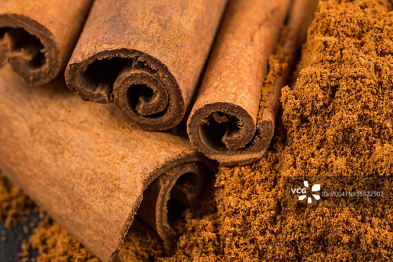 深色石板上的肉桂棒与粉末图片素材
