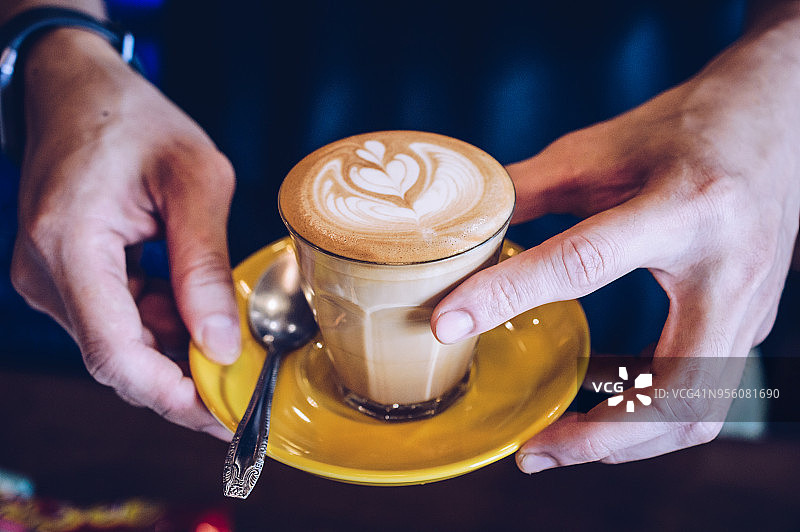 手持拿铁咖啡玻璃杯的特写镜头图片素材