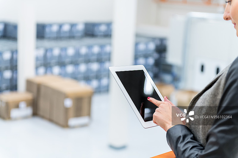 使用平板电脑和仓库里的箱子的女人图片素材
