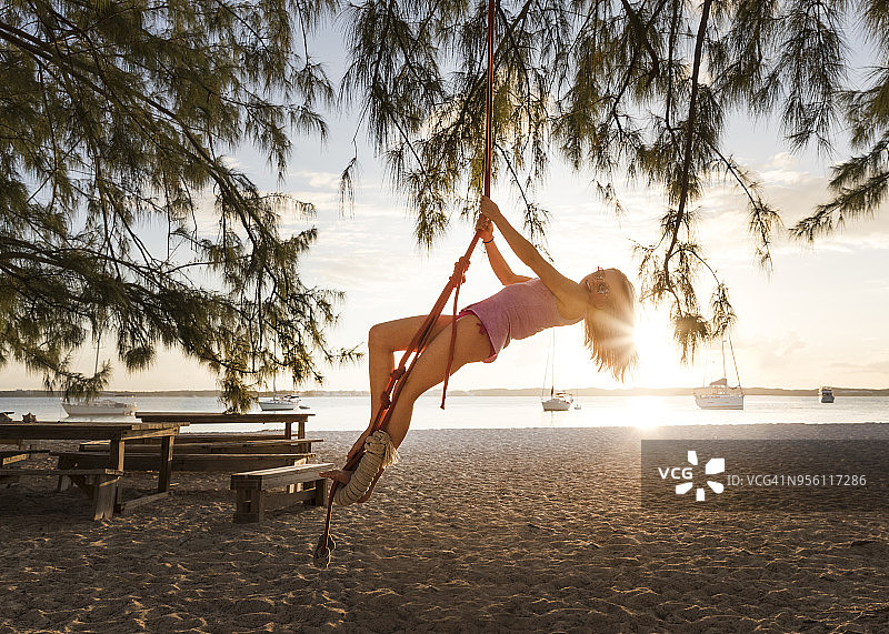 在巴哈马群岛埃克苏马斯群岛斯托金岛海滩上玩绳索秋千的女孩图片素材
