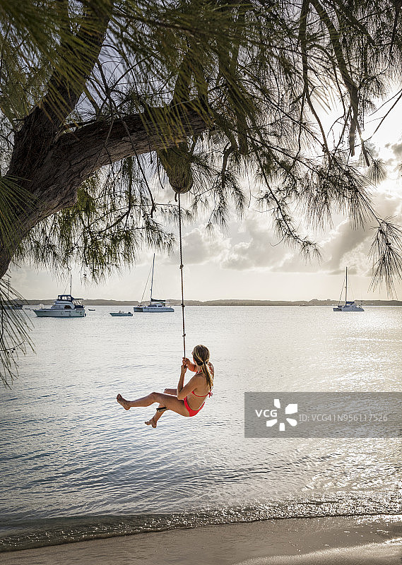 在斯托金岛_埃克苏马斯群岛_巴哈马海滩水上的绳索秋千上的女孩图片素材