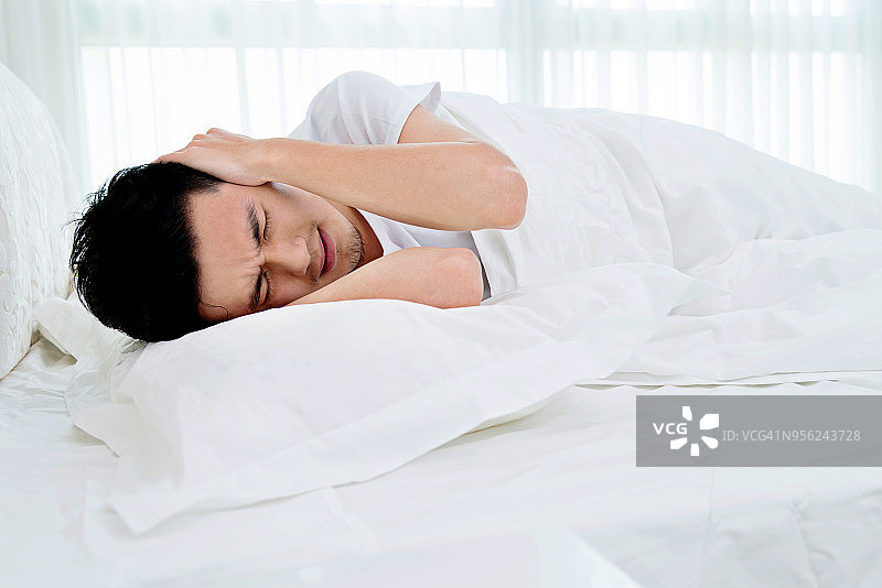 在床上感到不舒服的年轻人图片素材