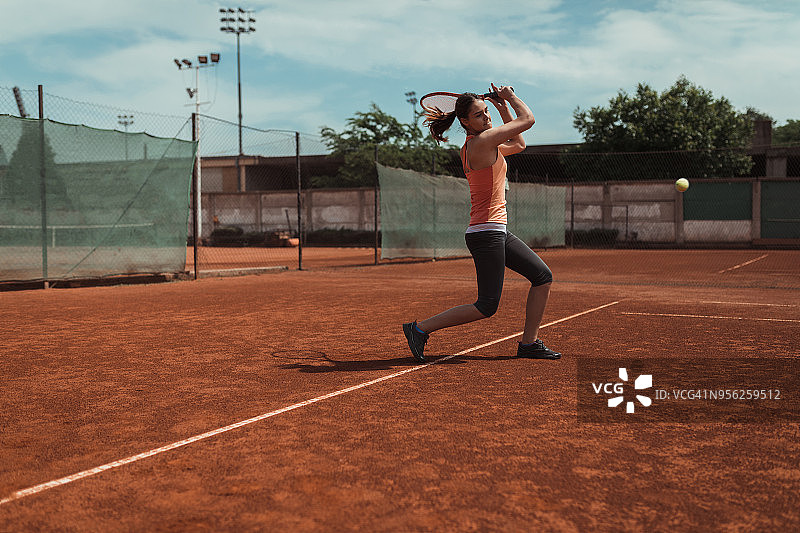 在户外红土球场上打网球的女人图片素材