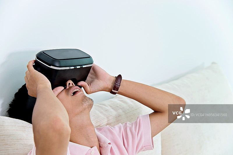 在家使用VR模拟器头显的年轻男人图片素材