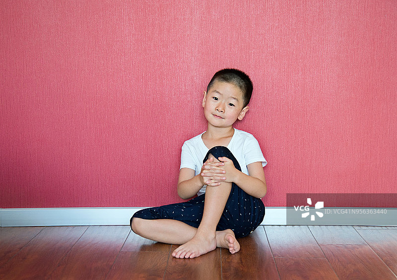 小男孩靠墙坐在地板上图片素材