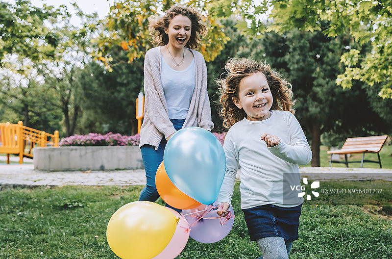 阳光明媚的日子里，快乐的女孩和她的母亲在户外玩耍图片素材