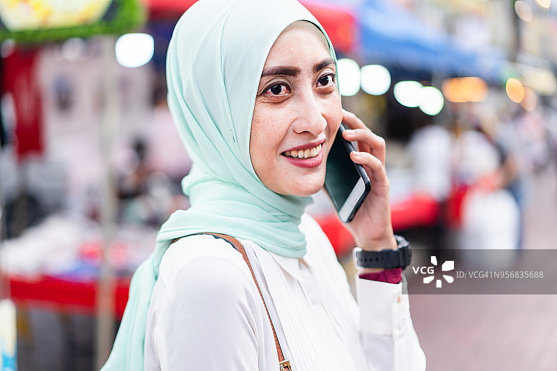 穆斯林女人在繁忙街道打电话图片素材
