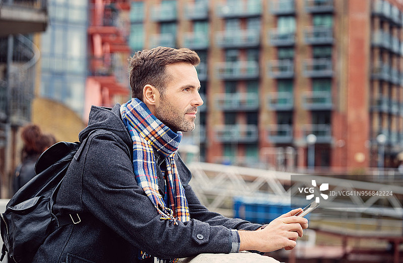 户外照片：拿着手机，看向远方的英俊男人图片素材
