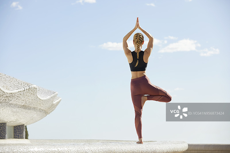 女子在楼顶露台做树式瑜伽图片素材
