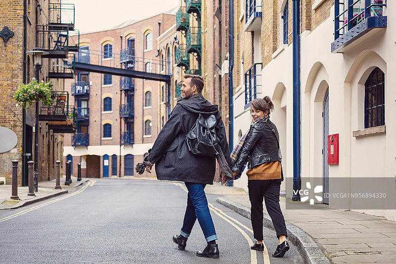 在街上手牵手散步的快乐情侣图片素材