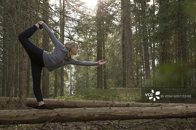 女子在森林的圆木上做瑜伽动作图片素材