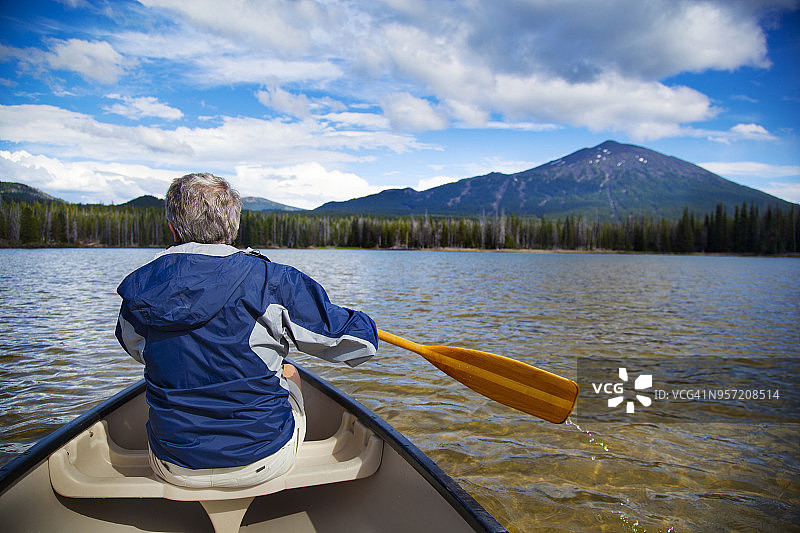 男人在湖中划船驶向山脉的背影图片素材
