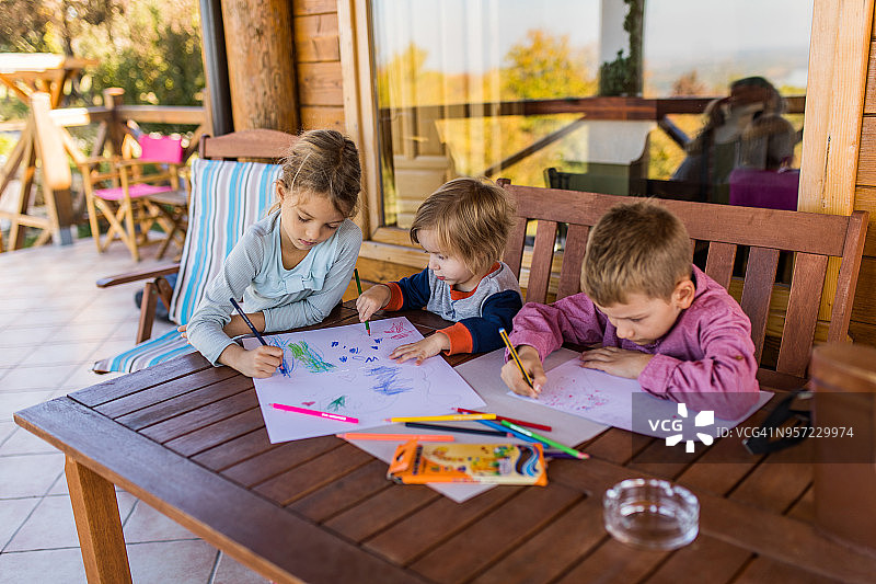 小孩在露台上用彩色蜡笔画画图片素材