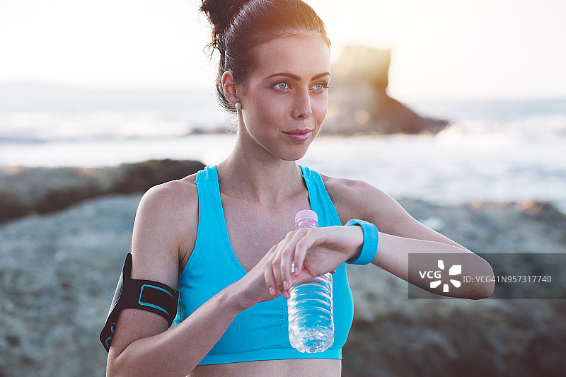 跑步者在海滩慢跑后用智能手表检查心率图片素材