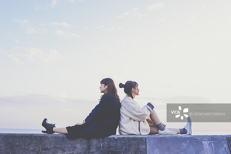 两名年轻女子背靠背坐着图片素材