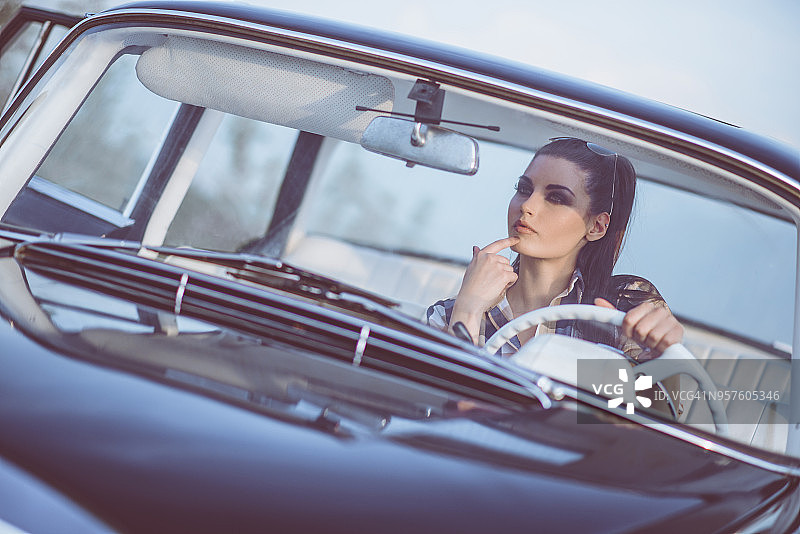 日落时分，在老爷车里有魅力的复古风格女人图片素材