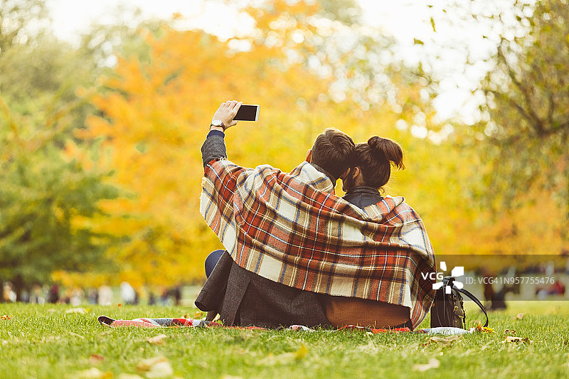 情侣在秋季周末在公园自拍的背影图片素材