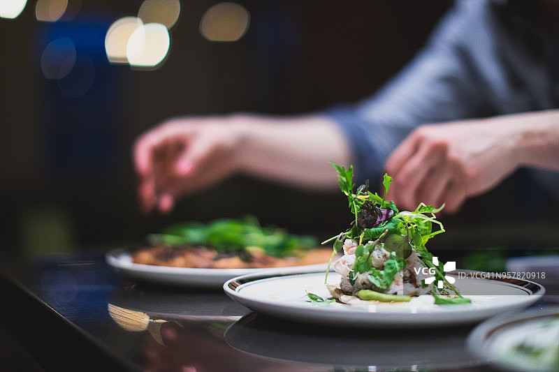 厨师在餐厅厨房准备多盘菜肴，餐饮服务图片素材