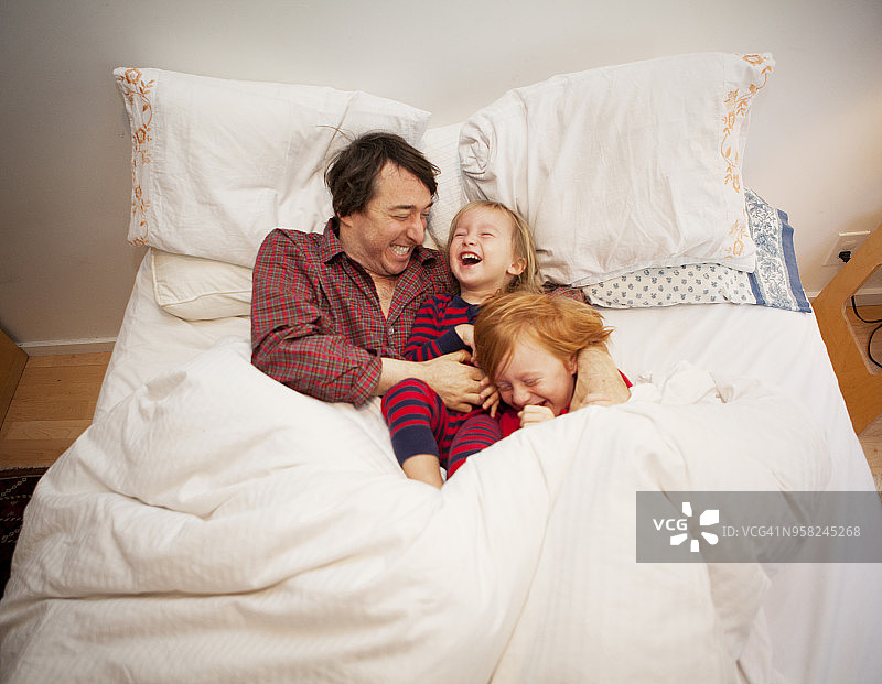 父亲在家里的床上和儿子们玩耍图片素材