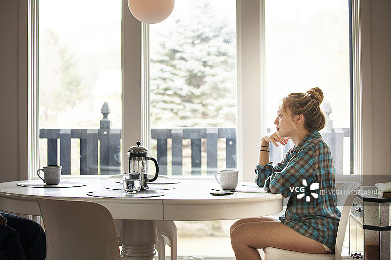 女子在自家早餐桌旁就座的侧面视角图片素材