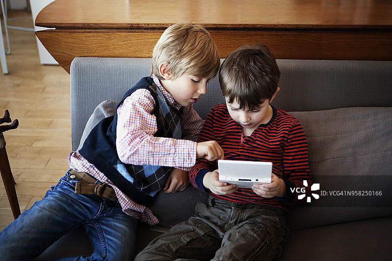 兄妹在家坐在沙发上玩电子游戏的俯视照片图片素材