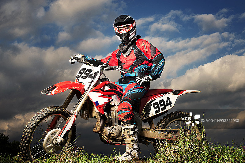 自信的越野车手在多云天空下的田野上的全身像图片素材