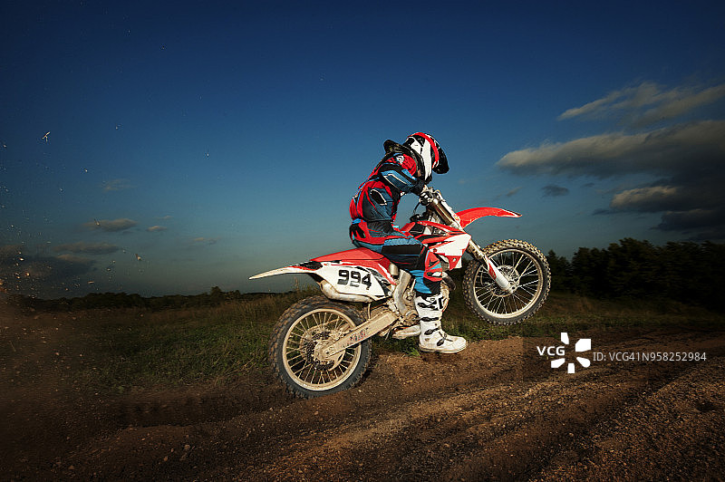 男子在黄昏时分骑越野摩托车的侧面视角图片素材