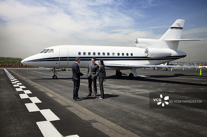 商务人士在跑道上对着公务机进行讨论图片素材