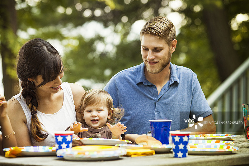 幸福的家庭：坐在森林里的野餐桌旁图片素材